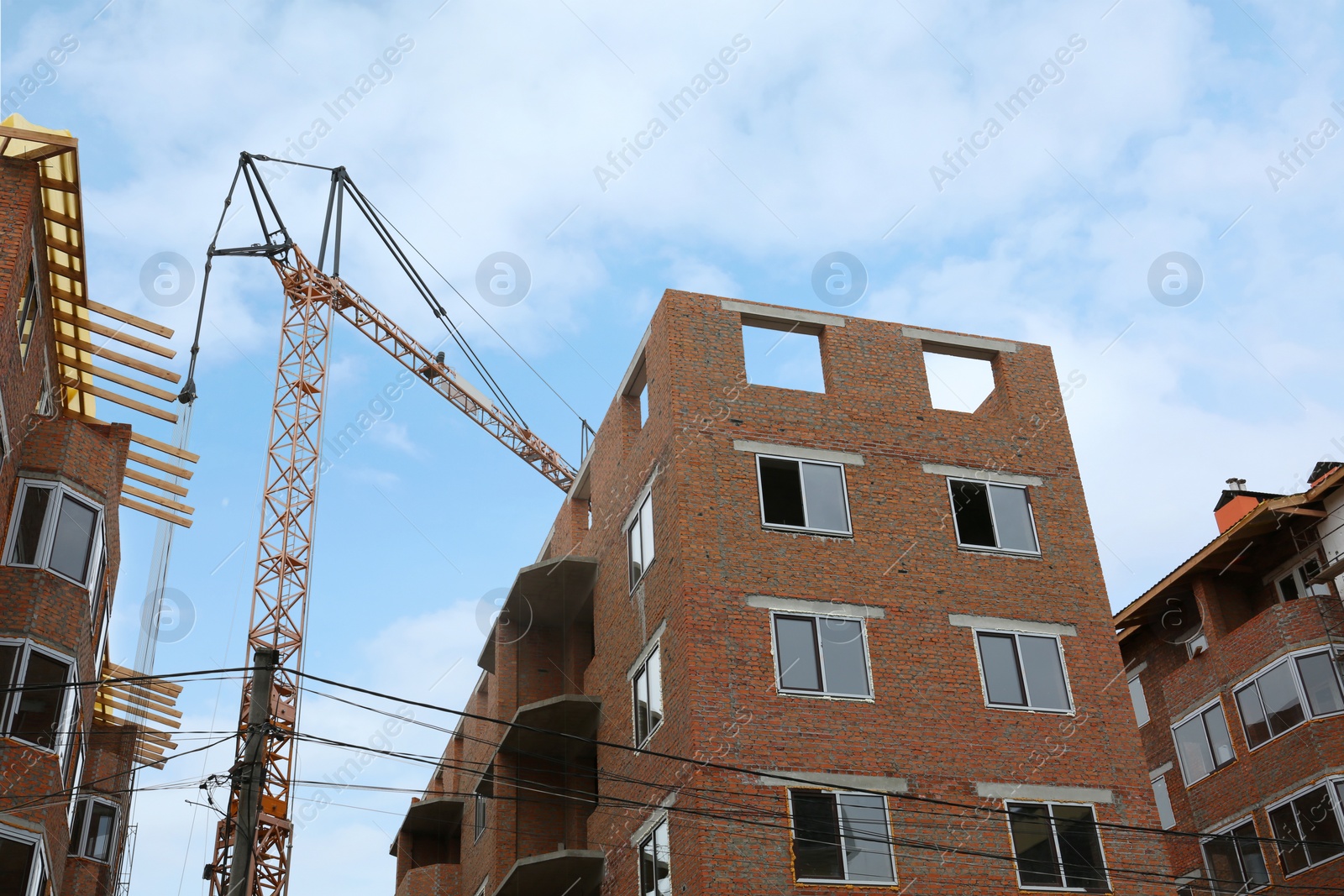 Photo of Construction site with tower crane near unfinished buildings, low angle view