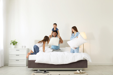 Photo of Happy family having pillow fight in bedroom