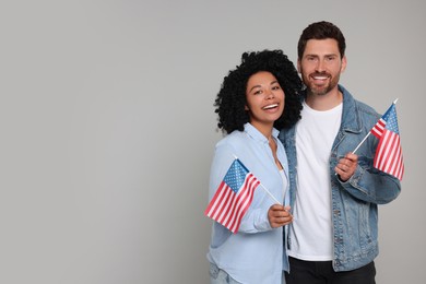Photo of 4th of July - Independence Day of USA. Happy couple with American flags on grey background, space for text