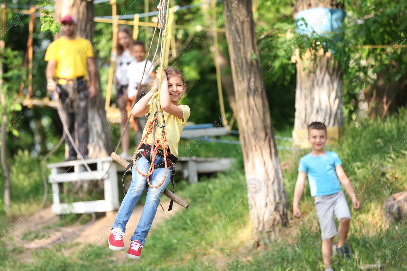 Photo of Little girl on zip line in adventure park. Summer camp