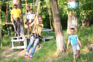 Little girl on zip line in adventure park. Summer camp