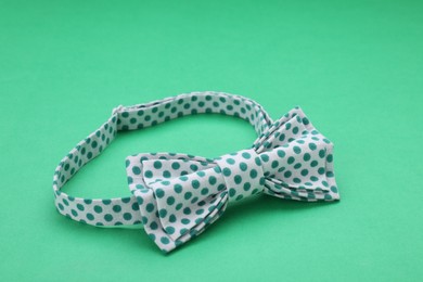 Photo of Stylish bow tie with polka dot pattern on green background
