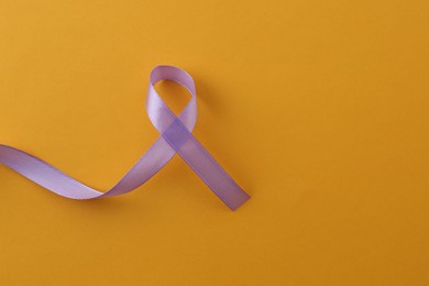 Violet awareness ribbon on orange background, top view. Space for text