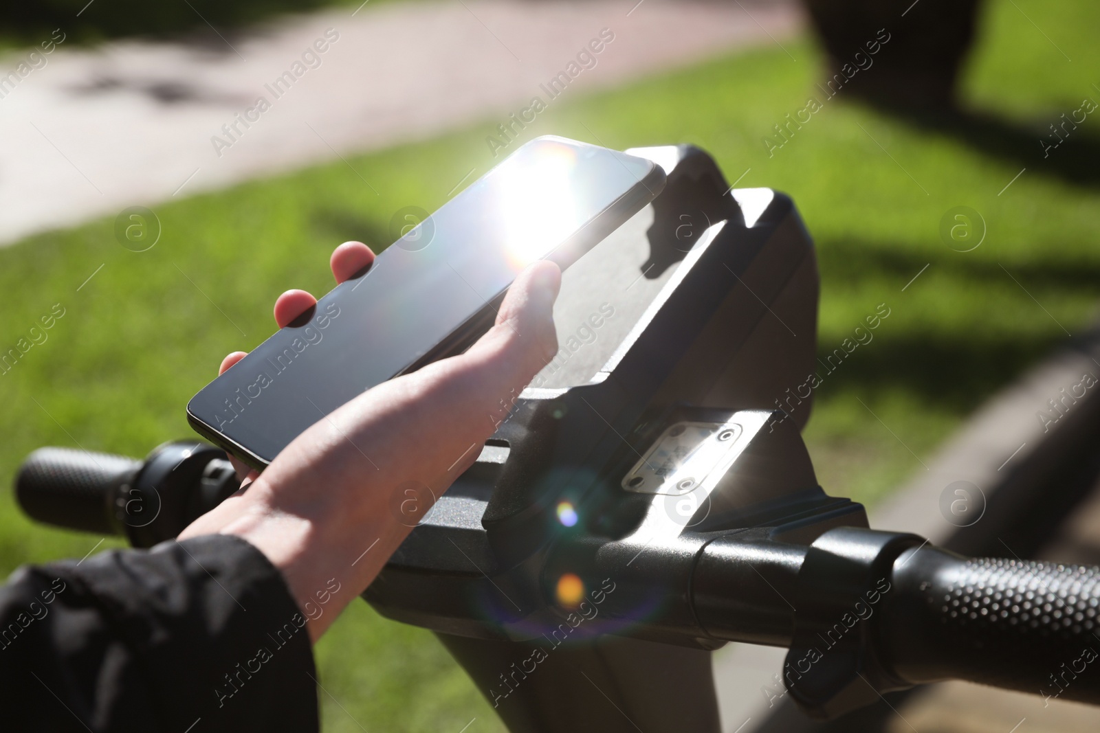 Photo of Man using smartphone to pay and unblock rental electric scooter outdoors, closeup