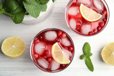 Photo of Tasty refreshing cranberry cocktails with lemon on white wooden table, flat lay