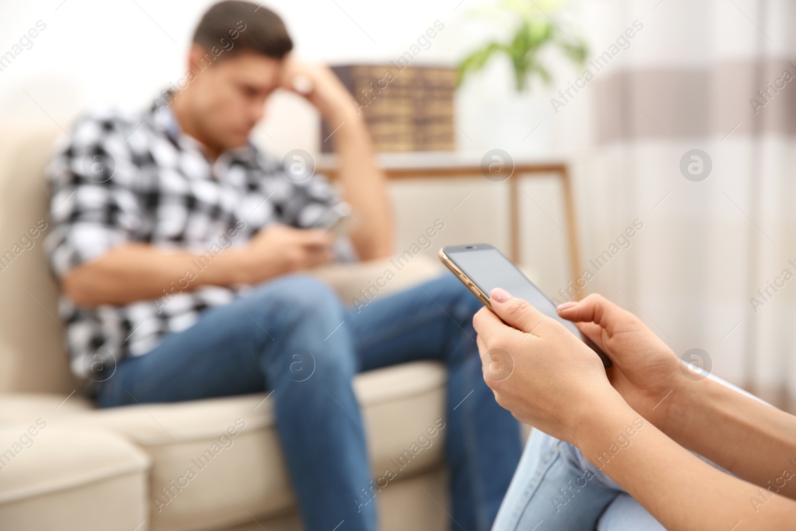 Photo of Couple addicted to smartphones ignoring each other at home, focus on hands. Relationship problems