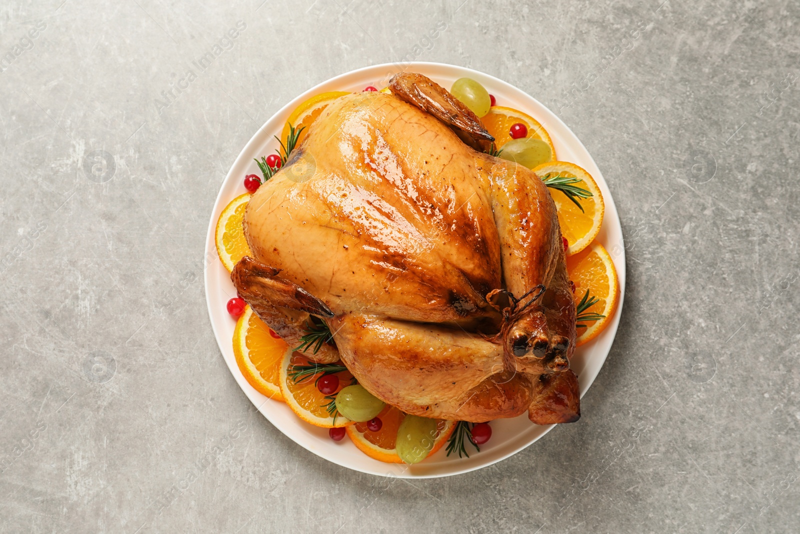 Photo of Platter of cooked turkey with garnish on grey background, top view