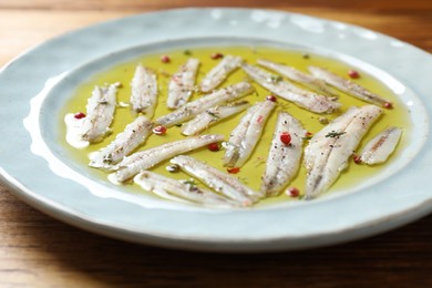 Tasty pickled anchovies with spices on wooden table, closeup