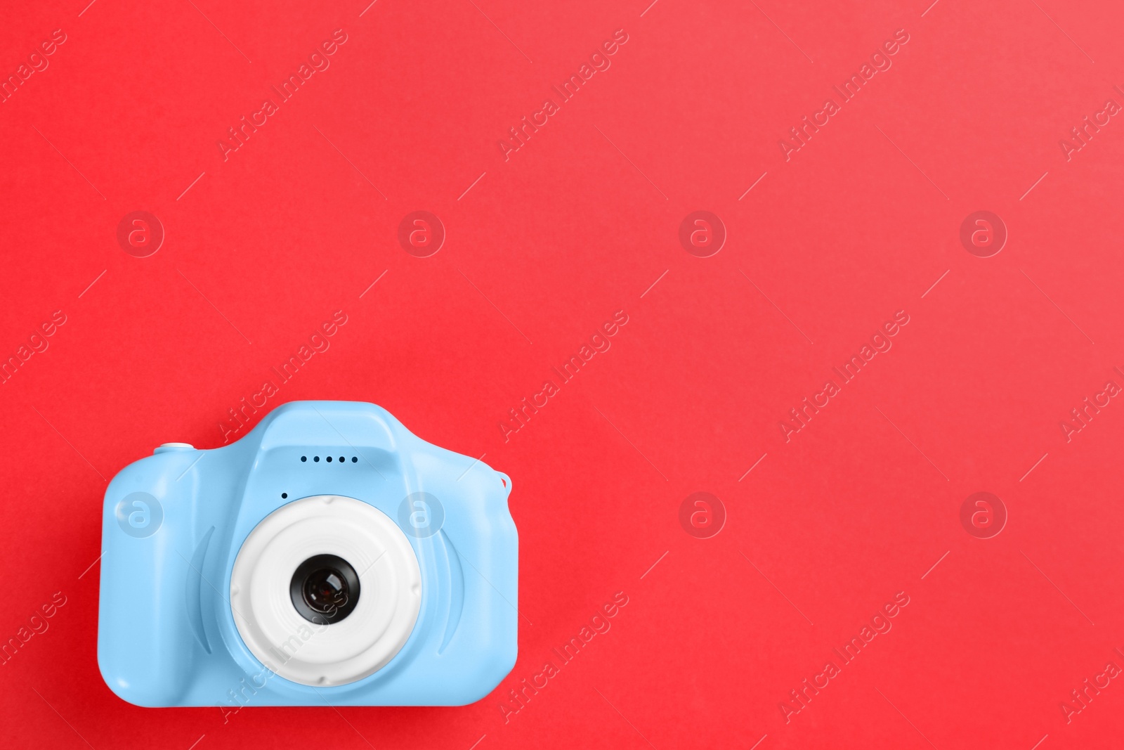 Photo of Light blue toy camera on red background, top view. Space for text