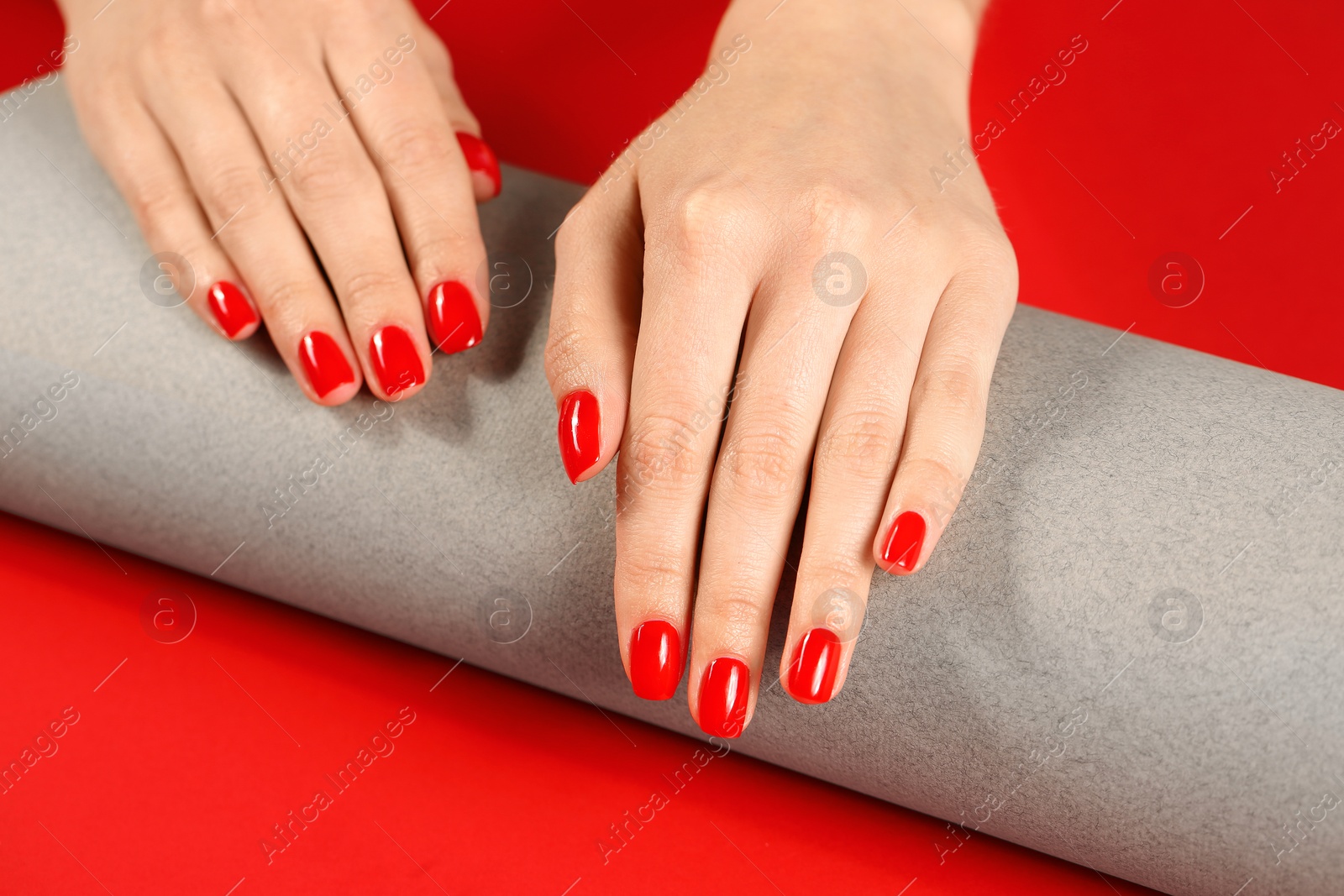 Photo of Woman showing manicured hands with red nail polish on color background, closeup