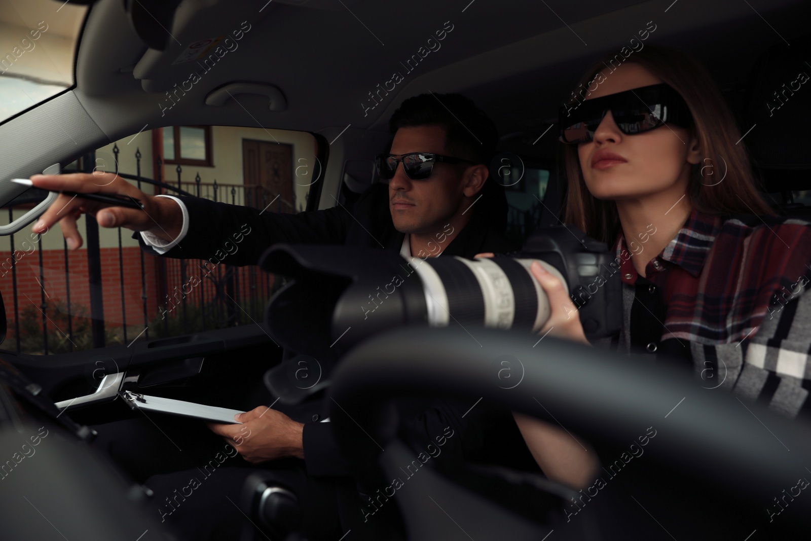 Photo of Private detectives with modern camera spying from car