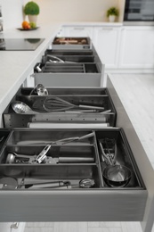 Photo of Open drawers with different utensils in kitchen