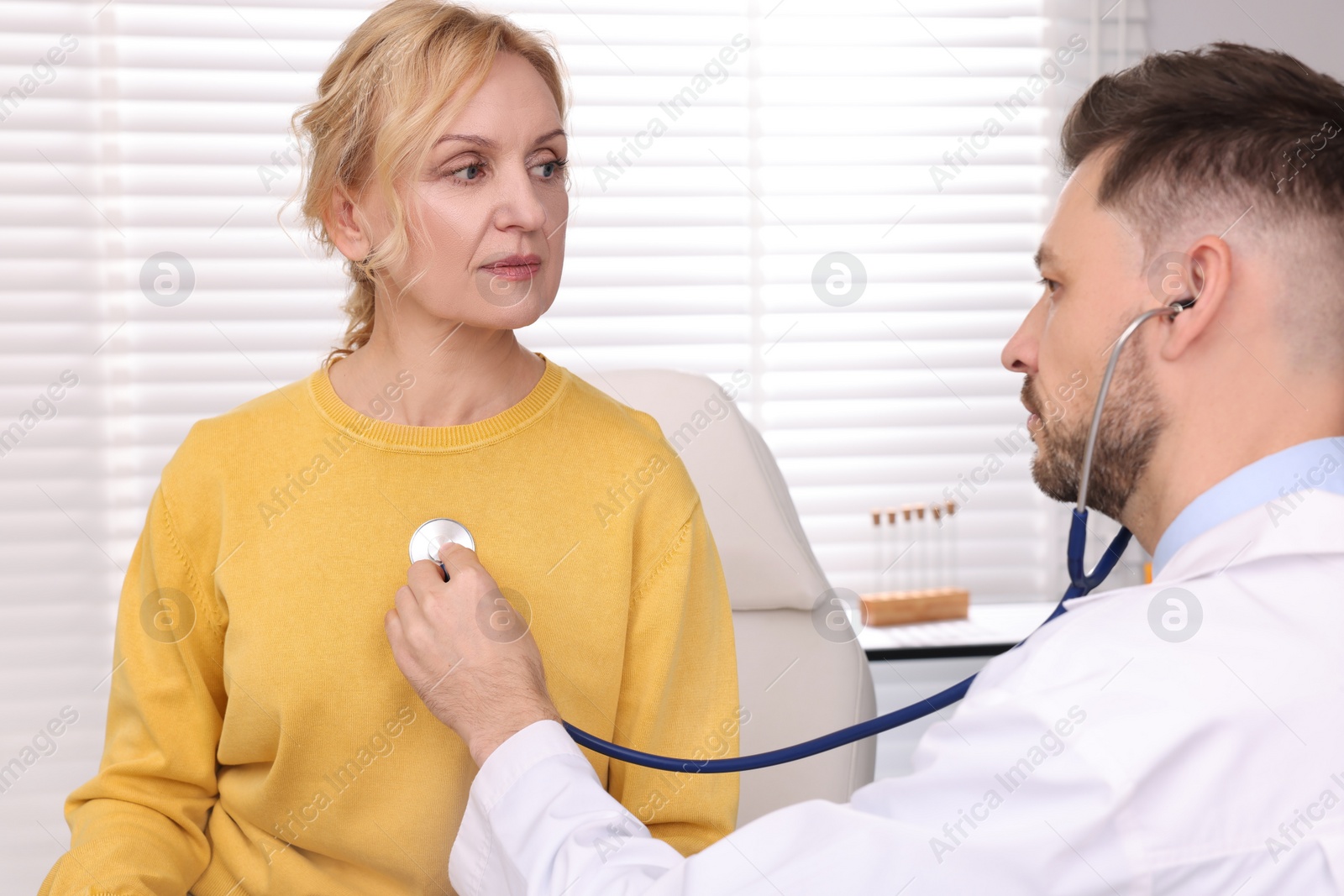 Photo of Doctor listening to patient's lungs with stethoscope in clinic