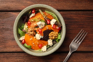 Delicious persimmon salad with cheese and pomegranate served on wooden table, flat lay