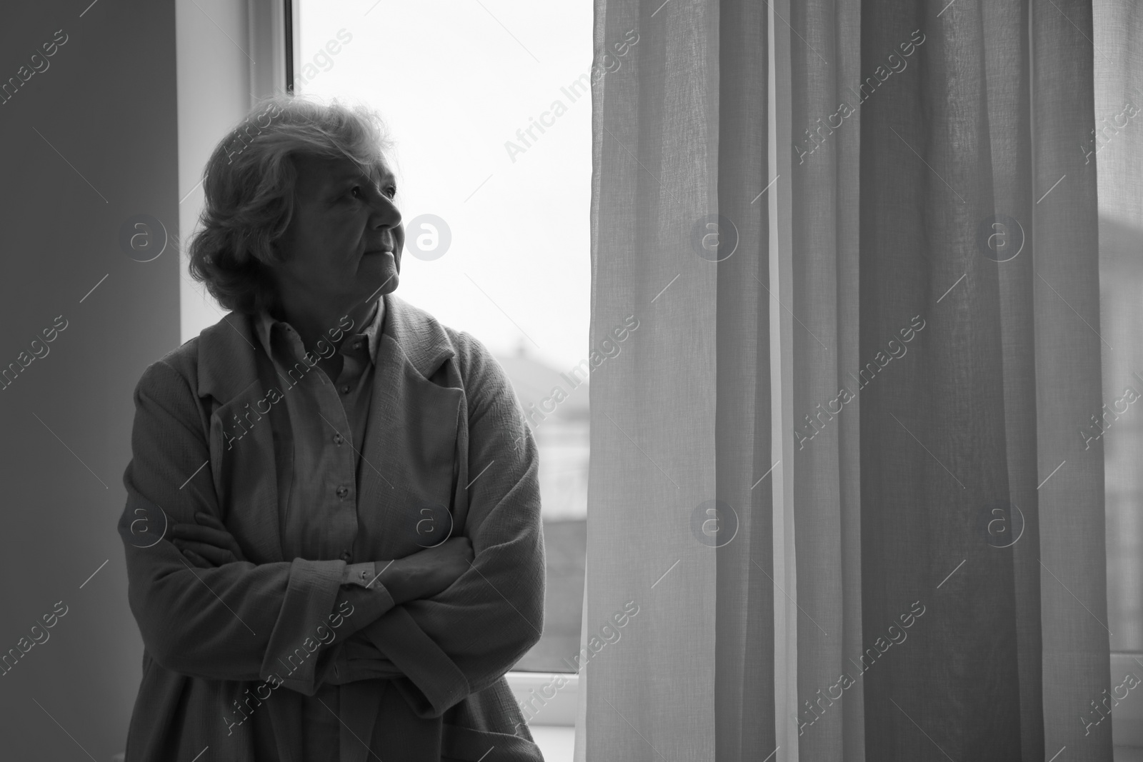 Photo of Portrait of elderly woman near window indoors, space for text. Black and white effect