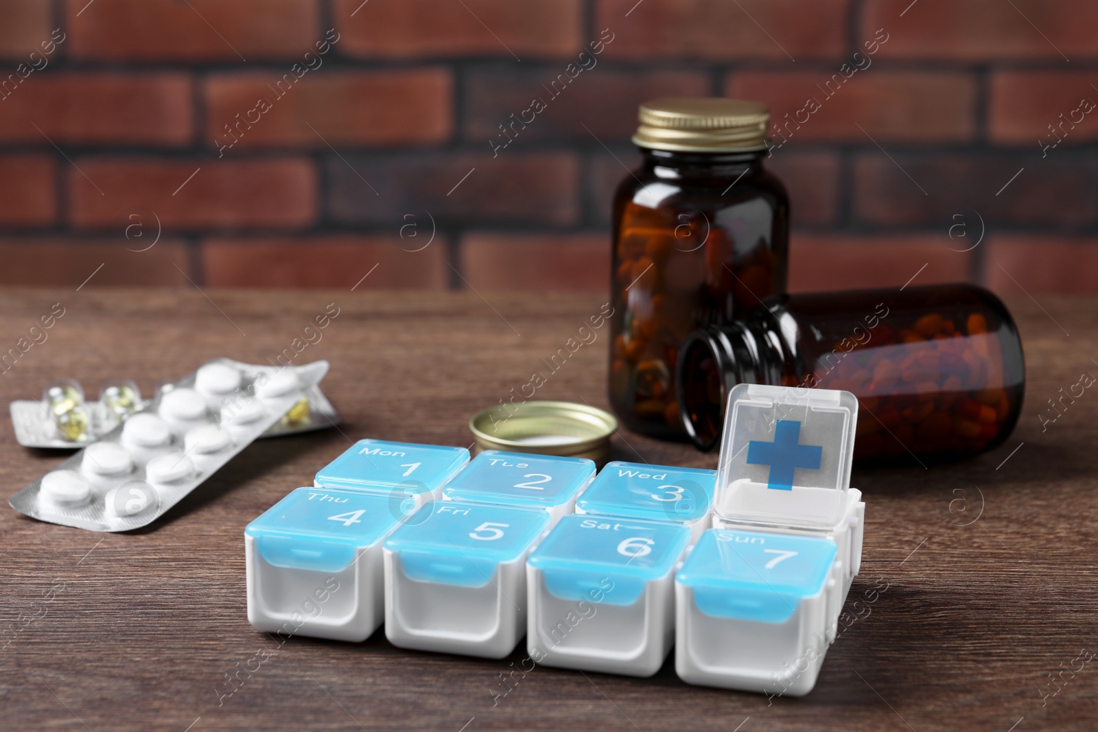 Photo of Weekly pill box with medicaments on wooden table