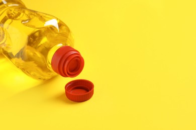 Plastic bottle of cooking oil on yellow background. Space for text