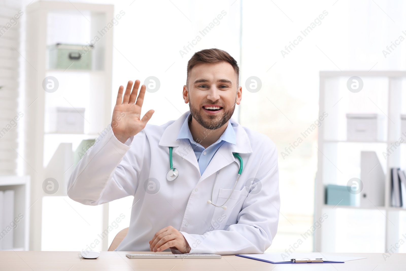 Photo of Male doctor using video chat at workplace, view from camera perspective