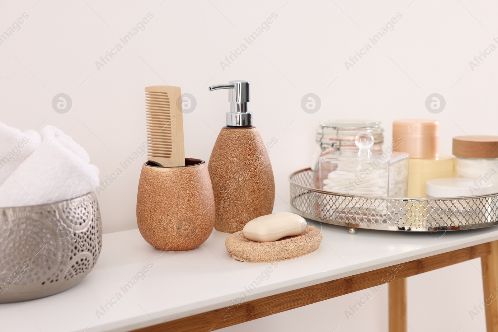 Photo of Different bath accessories and personal care products on table near white wall