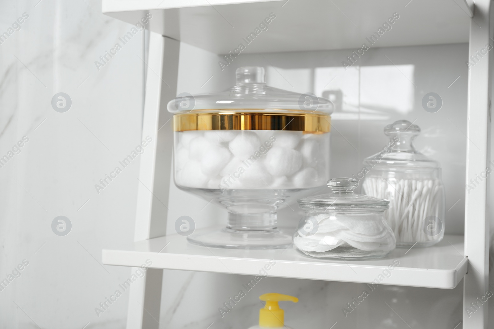 Photo of Cotton balls, swabs and pads on white shelf in bathroom