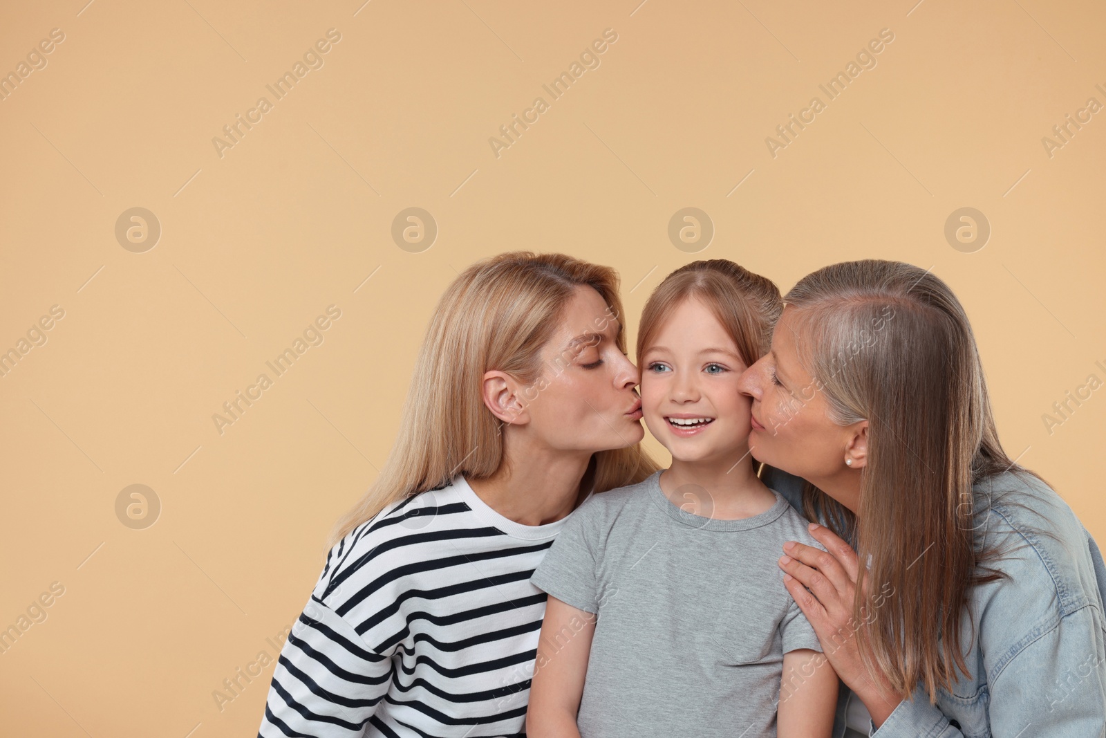 Photo of Three generations. Happy grandmother, her daughter and granddaughter on beige background, space for text