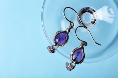 Beautiful pair of silver earrings with amethyst gemstones on blue background, above view