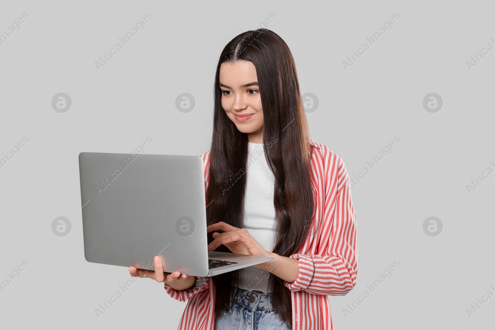 Photo of Teenage girl with laptop on light grey background