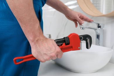 Photo of Professional plumber fixing water tap in bathroom, closeup