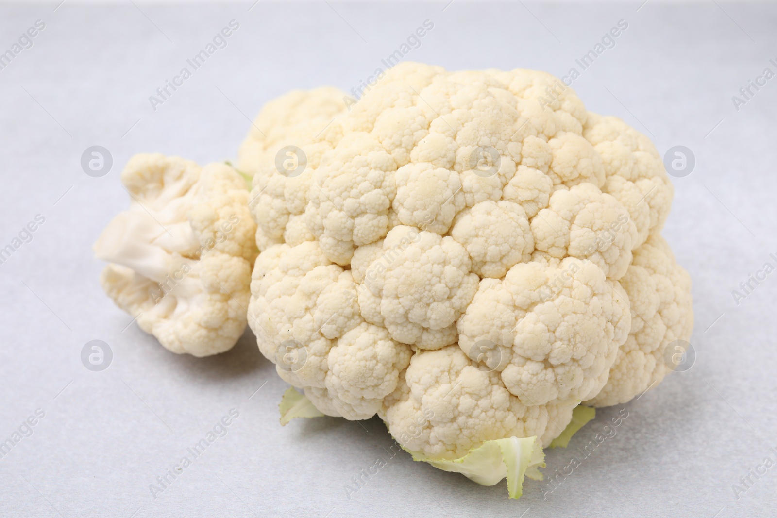 Photo of Cut fresh raw cauliflower on light grey table