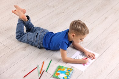 Photo of Cute little boy drawing on warm floor at home. Heating system