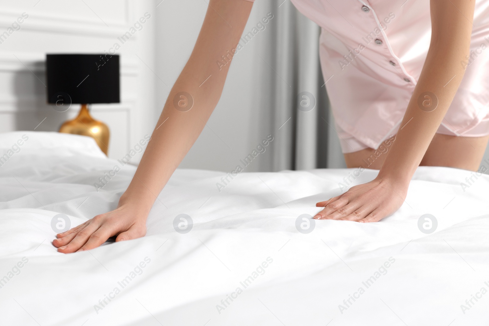 Photo of Young woman making bed in room, closeup