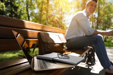 Photo of Man taking break during work in park, focus on laptop