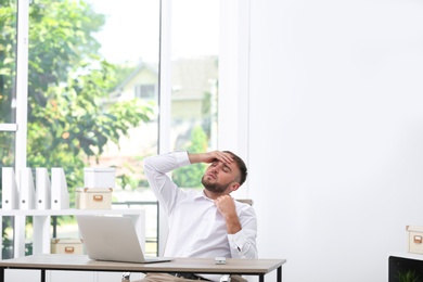 Photo of Young man suffering from heat in office. Air conditioner malfunction