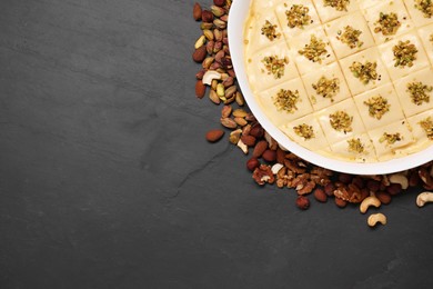 Making delicious baklava. Raw dough with different nuts on black textured table, flat lay. Space for text