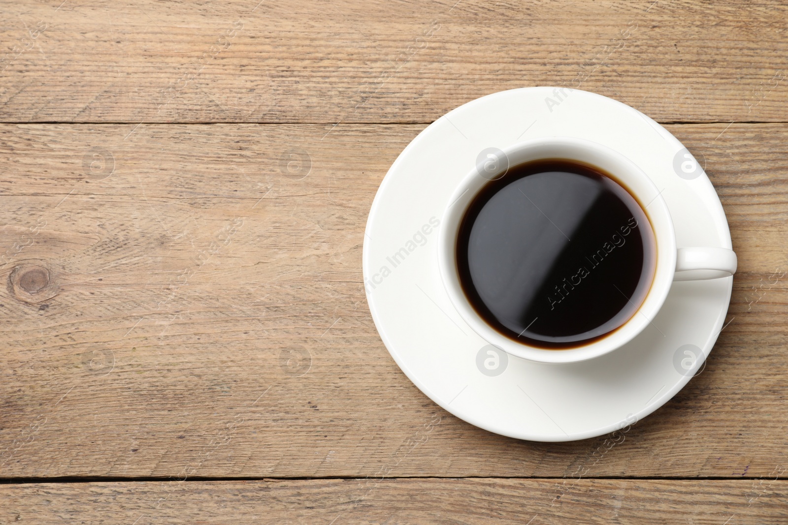 Photo of Cup of aromatic coffee on wooden table, top view. Space for text