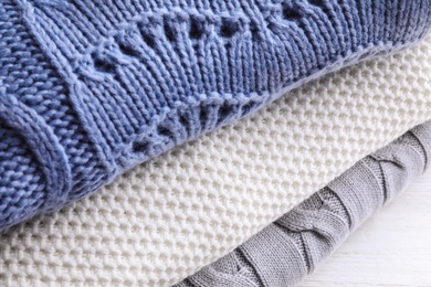 Photo of Stack of soft knitted sweaters on table, closeup