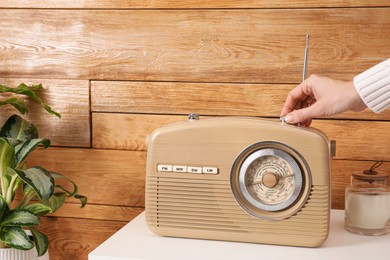 Woman turning volume knob on radio indoors, closeup