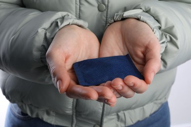 Woman holding hand warmer on white background, closeup