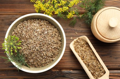 Photo of Dry seeds and fresh dill on wooden table, flat lay