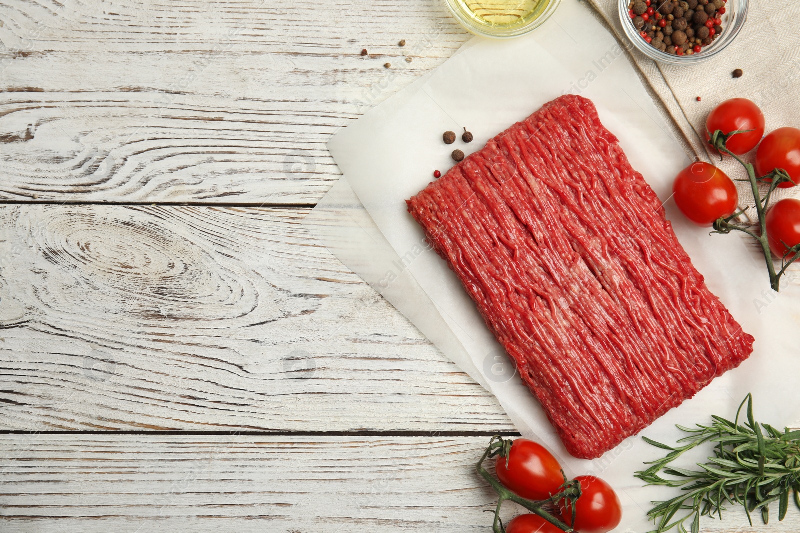 Photo of Raw fresh minced meat and other ingredients on white wooden table, flat lay. Space for text