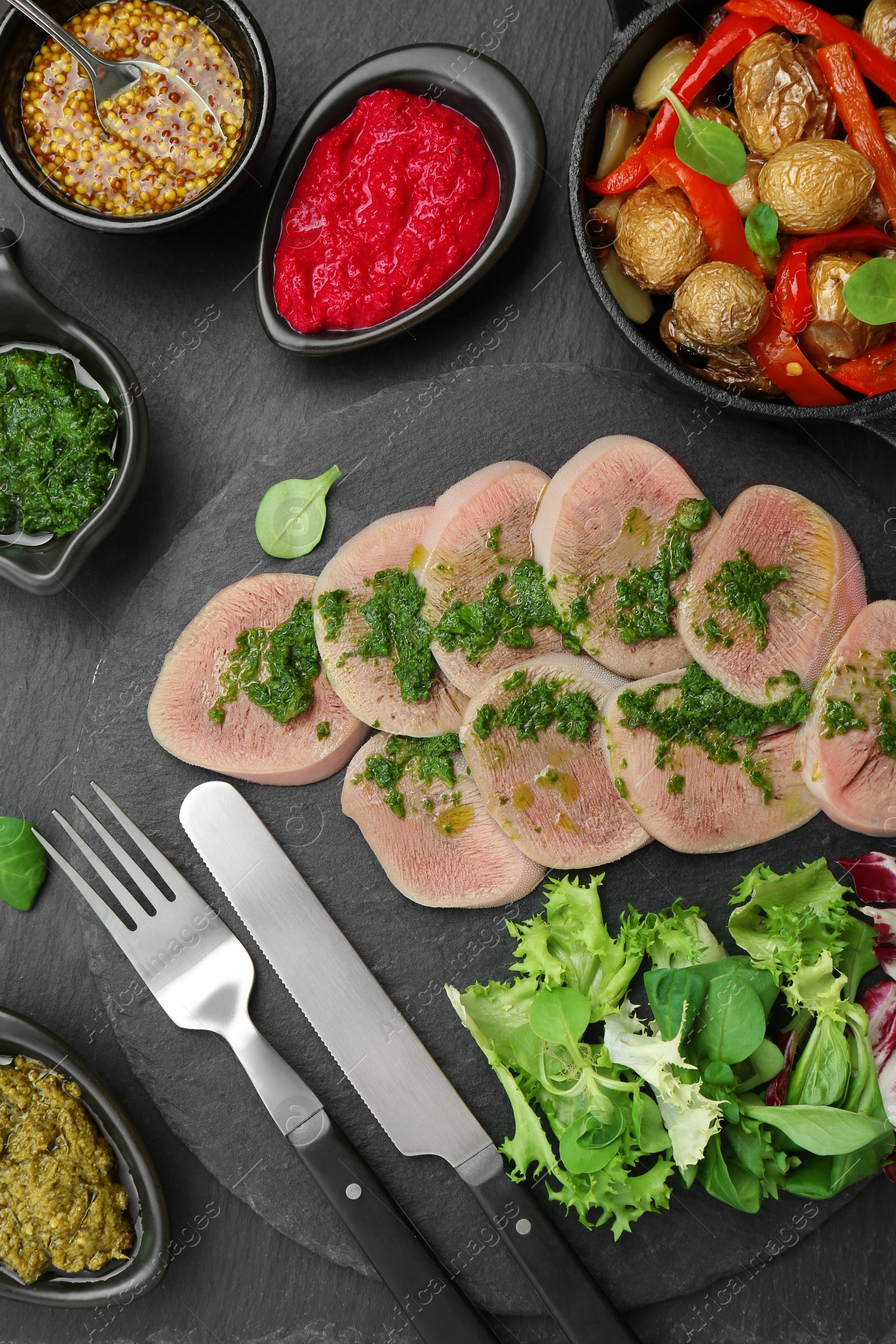 Photo of Tasty beef tongue pieces and ingredients served on grey table, flat lay