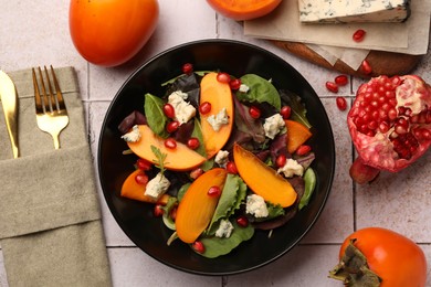 Photo of Delicious persimmon salad, knife and fork on tiled surface