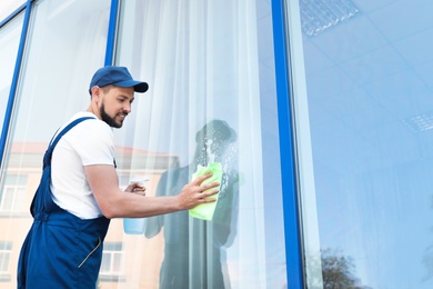 Photo of Male worker washing window glass from outside