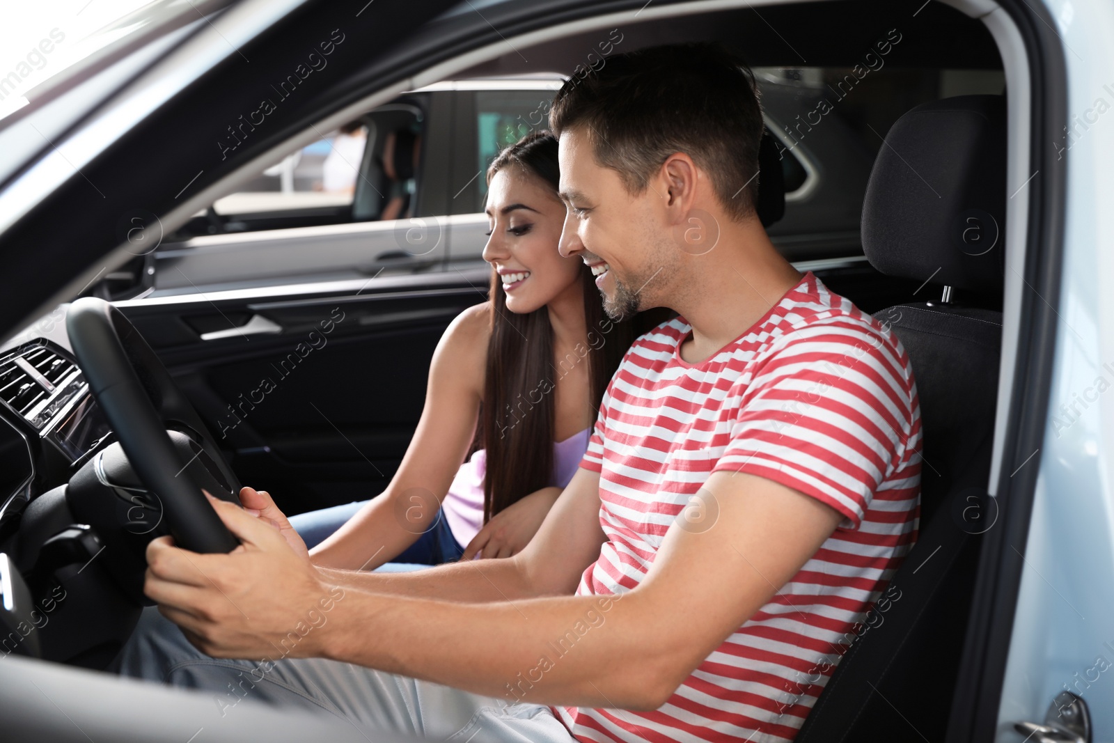 Photo of Young couple testing new car in salon