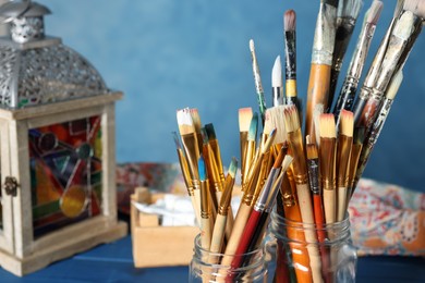Photo of Glass jars with many different paintbrushes, closeup