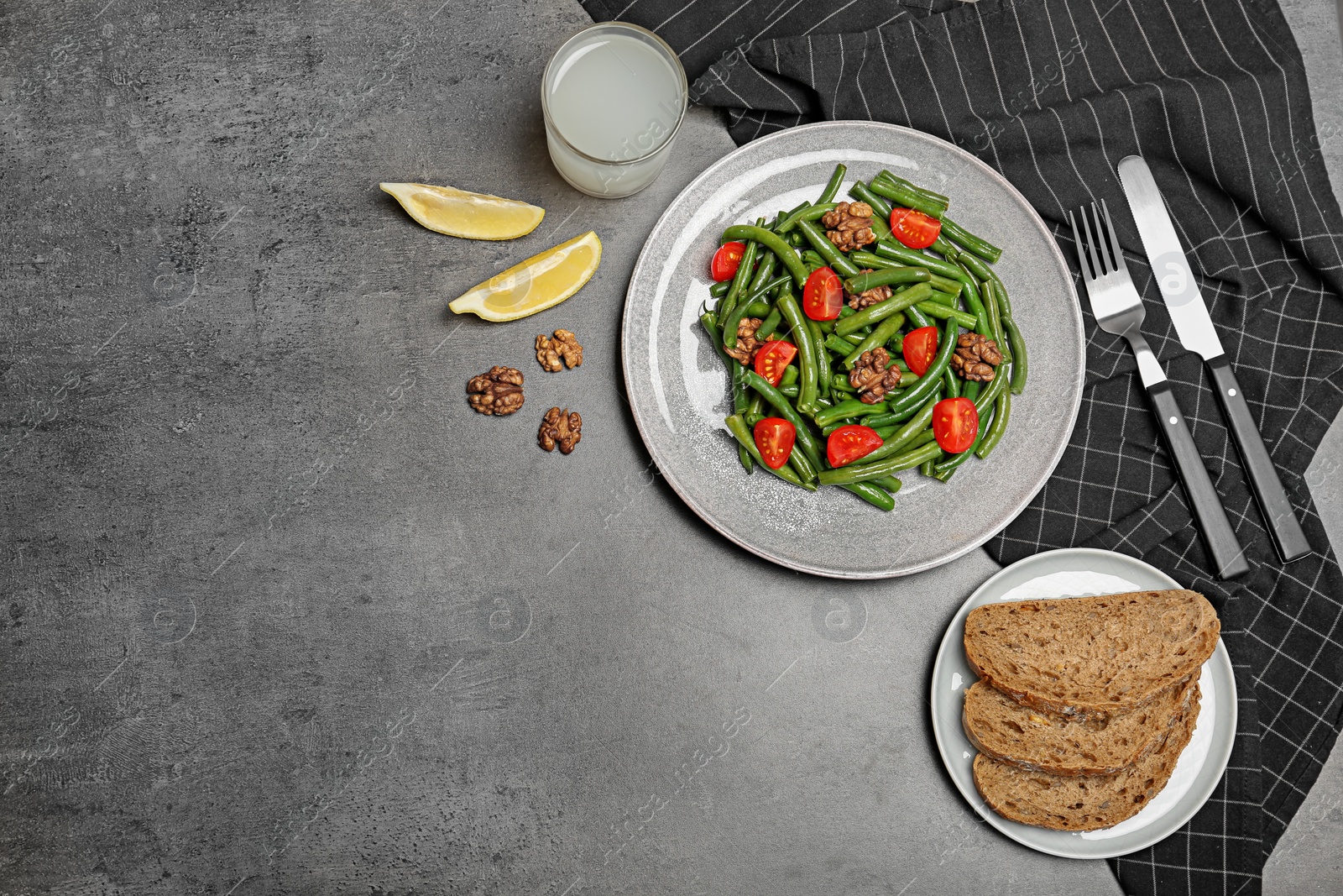 Photo of Plate with tasty green beans, tomatoes and nuts on table, top view