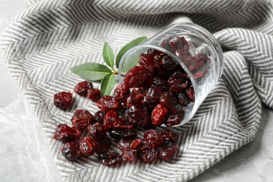 Photo of Overturned glass with tasty dried cranberries on table