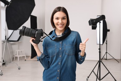 Photo of Professional photographer with camera showing thumbs up in modern photo studio