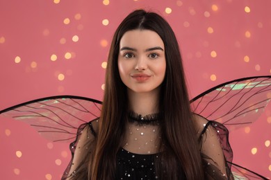 Beautiful girl in fairy costume with wings on pink background