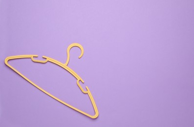 Empty clothes hanger on violet background, top view. Space for text